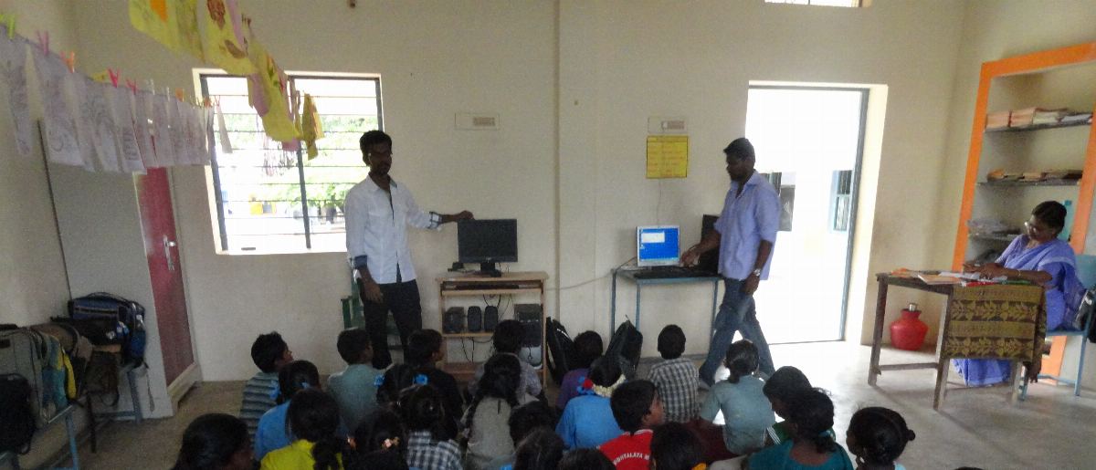 Sirpigal volunteers teaching computer basics to a class of children